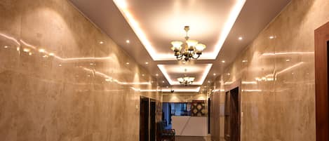A hallway with a marble floor, recessed lighting, and a chandelier.