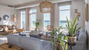 En rummelig stue med en stor sofa, et sofabord og havudsigt gennem store vinduer.