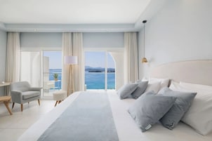 Una habitación de hotel moderna con una cama grande, un escritorio, una silla y vista al mar.