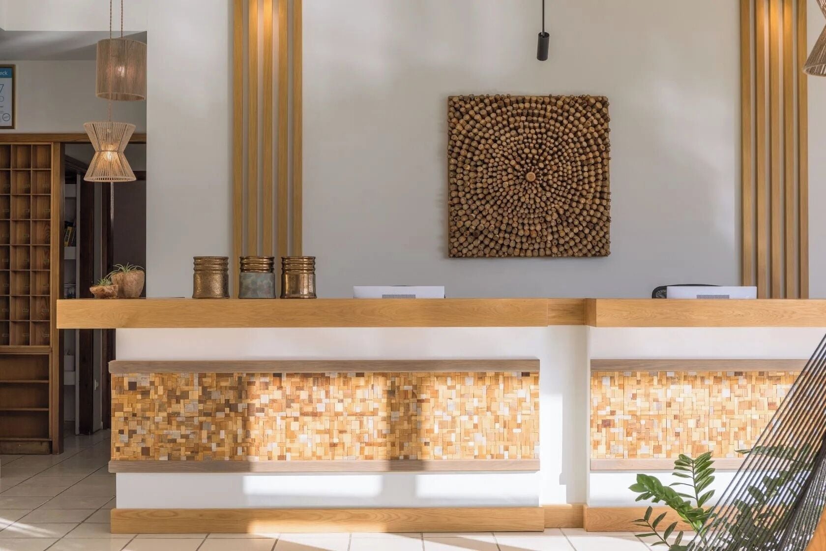 Un comptoir d’accueil avec un revêtement en bois, un panneau décoratif fixé au mur et un luminaire suspendu.