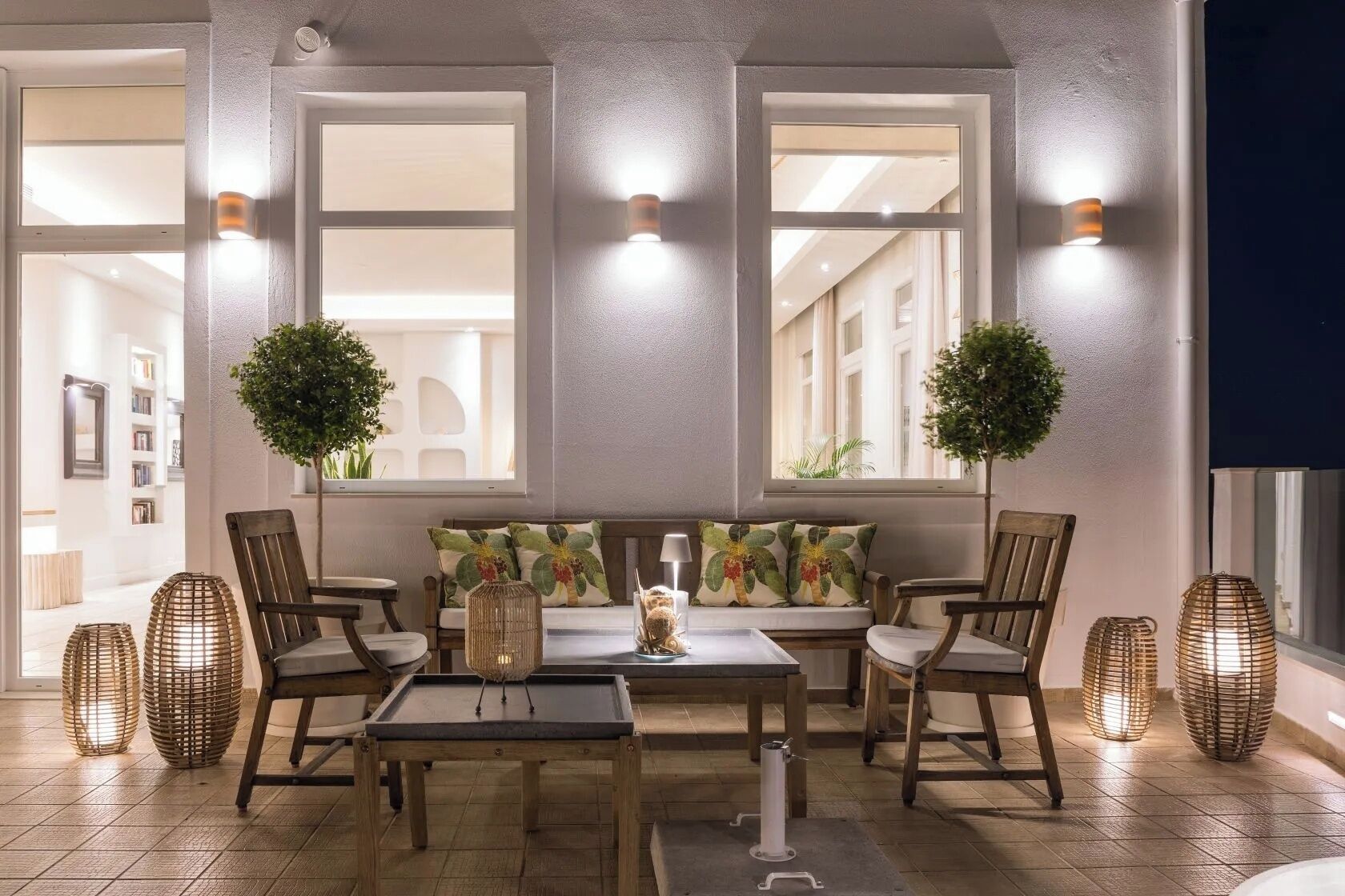 A room with a wooden bench, wicker lamps, and a view through large windows.