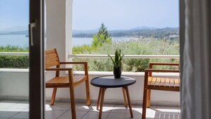 A balcony with two wooden chairs, a small round table, and a potted plant. - Marilena Sea View (Pirgi)