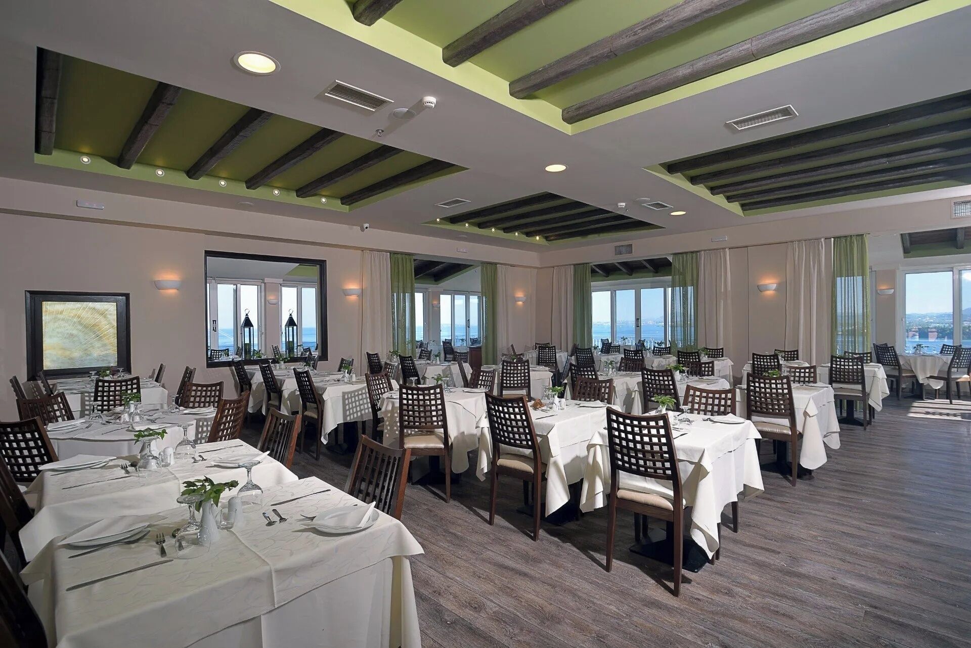 A spacious dining area with multiple tables, chairs, and large windows offering a view.