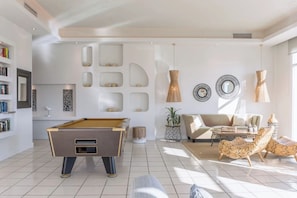 Una sala de estar moderna con una mesa de billar, un sofá y una mesa de centro.