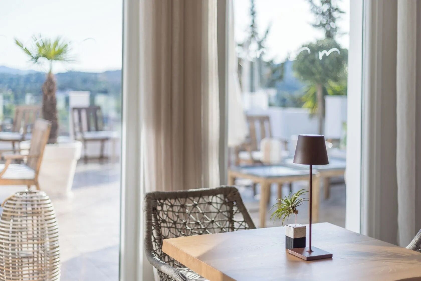 Un comedor con mesa, sillas, una lámpara y vistas amplias por las ventanas.