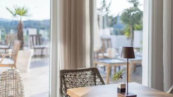 Un comedor con mesa, sillas, una lámpara y vistas amplias por las ventanas.