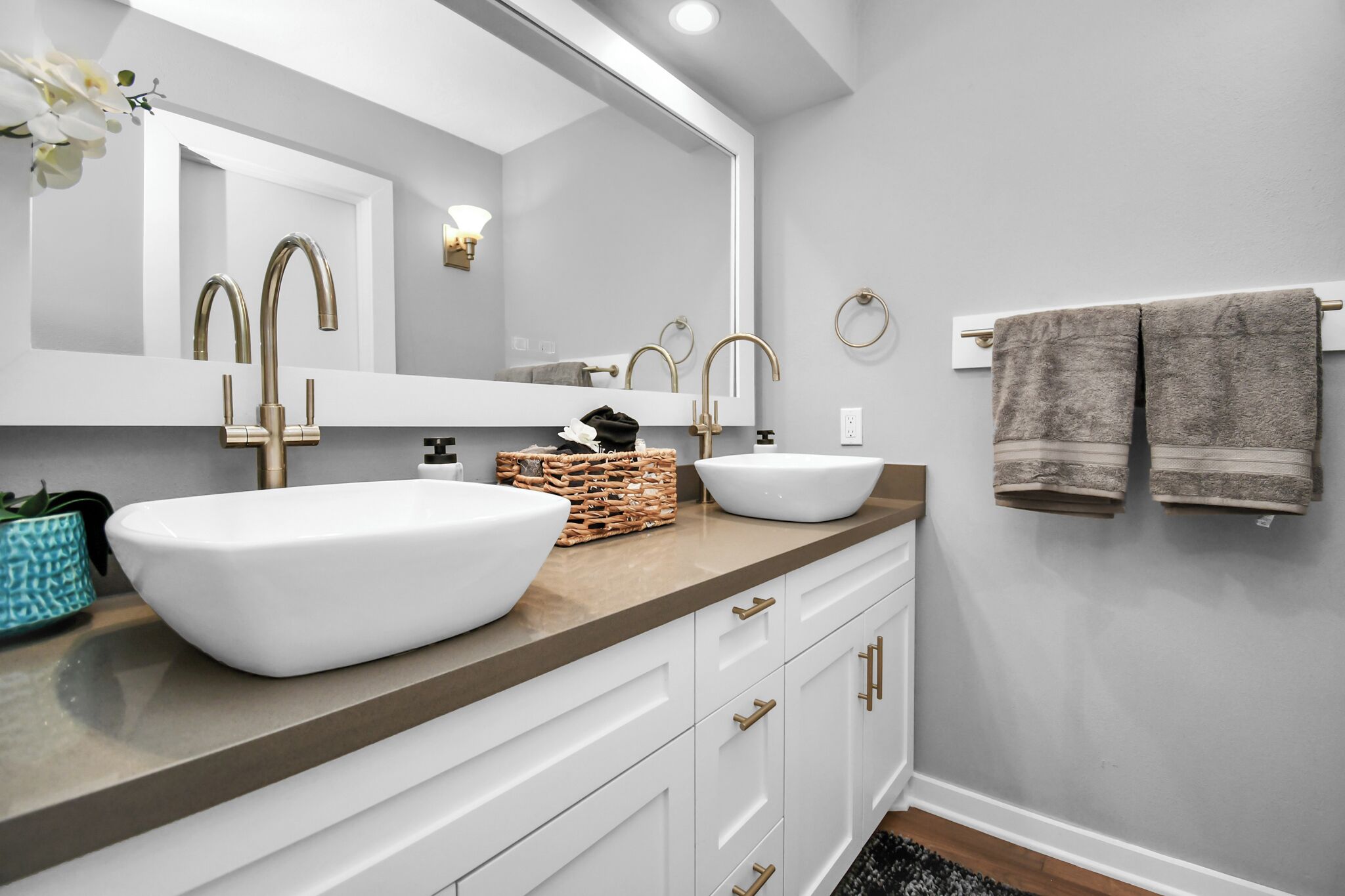 A bathroom with two sinks, a large mirror, and a towel rack.
