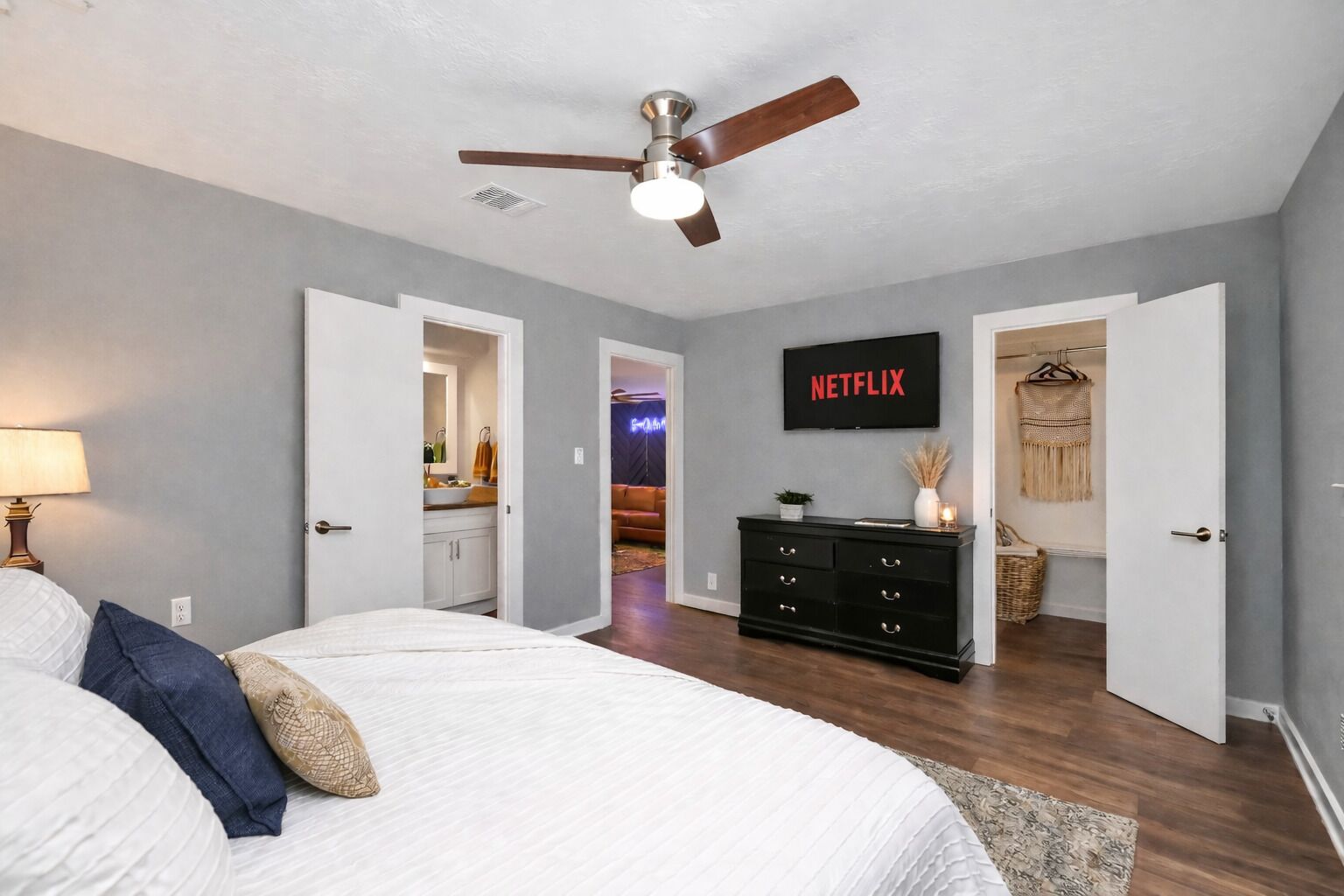 Une chambre à coucher avec un lit, un ventilateur de plafond, une télévision et une commode.