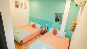Una habitación con dos camas, una mesita pequeña y un estante en la pared.