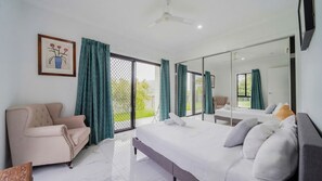 Quarto moderno com cama, sofá, poltrona e um espelho grande.