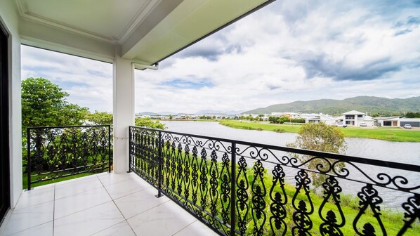 A balcony with a river view, white tiled floor, and a decorative black railing.