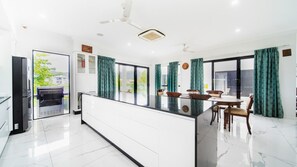 A modern kitchen with a central island, dining area with chairs, and a large window with curtains.