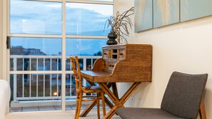 Ein Balkon mit einem Korbstuhl-Tisch, Stühlen und einem Blumentopf.