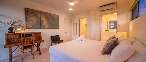 A hotel room with a bed, a desk, a chair, a ceiling fan, and a large window.