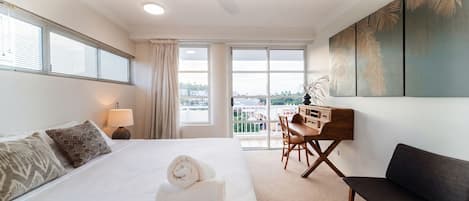 Habitación de hotel con cama, escritorio, silla, sofá y un amplio ventanal con vista a la ciudad.