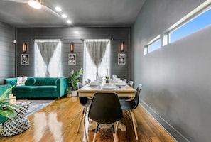 A dining area with a table set for six, a green sofa, and a plant. -  Spacious NOLA Home Near French Quarter (New Orleans)