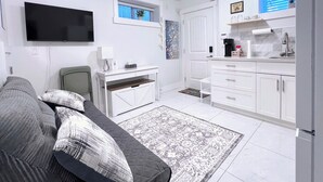 A compact living space with a sofa, a television, a kitchen area, and a small window.