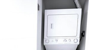 A compact, white laundry room with a washing machine and dryer, featuring a control panel with multiple dials and a small display screen.