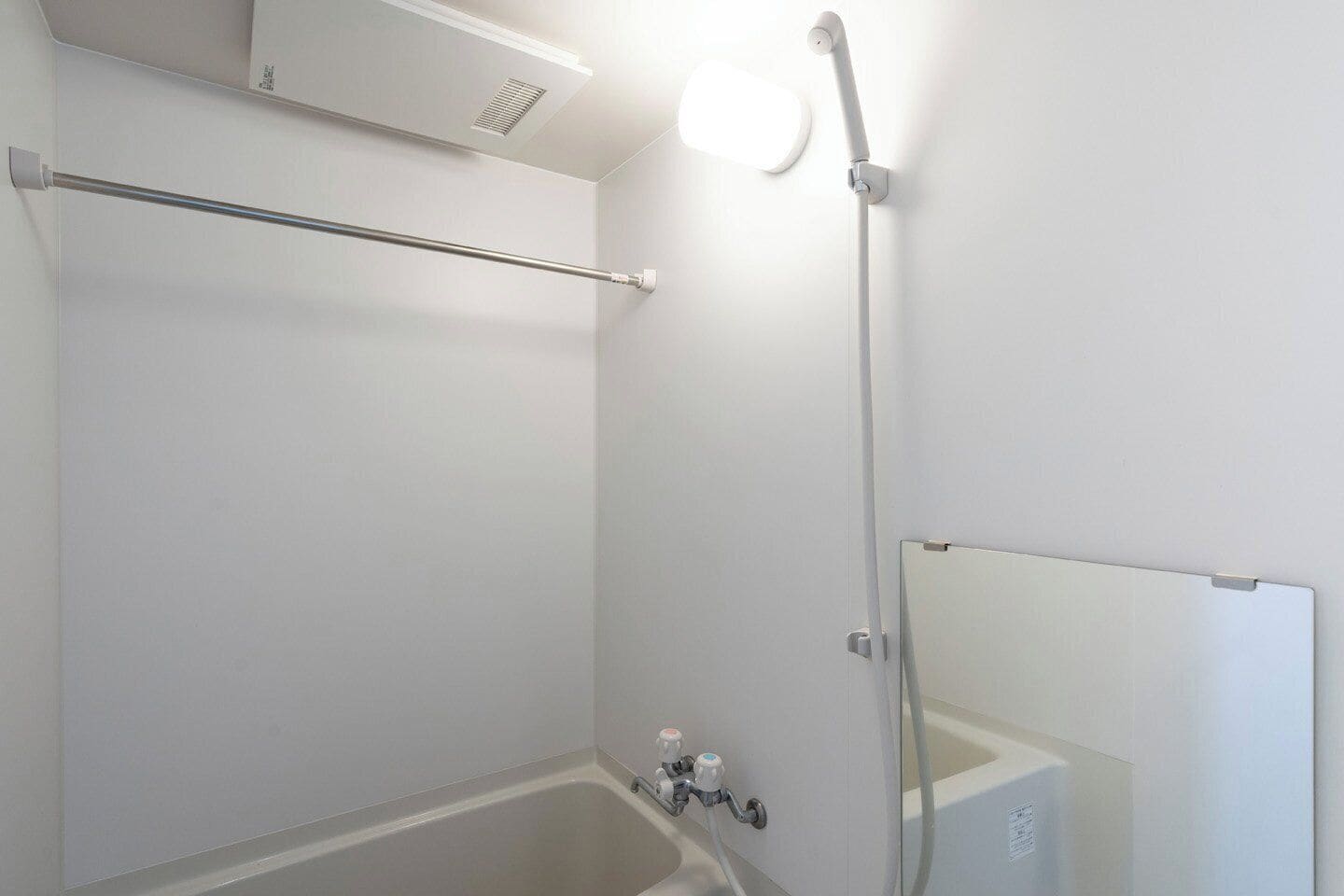 Ein Badezimmer mit Badewanne, Duschkopf, Handtuchhalter und Spiegel.
