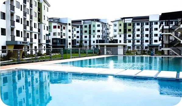 A swimming pool with a modern apartment complex in the background.