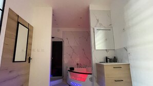 Moderni kylpyhuone, jossa on marmoriseinä, suihku, peilillä varustettu allastaso ja lattialämmitys.