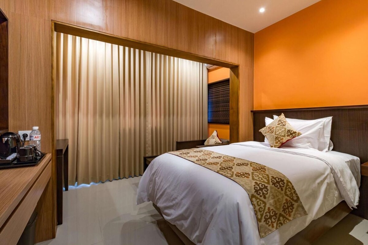 A hotel room with a bed, bedside table, and a water bottle.
