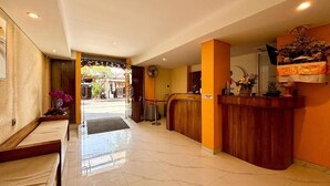 Un vestíbulo de hotel con recepción, zona de estar y vista despejada a la entrada.
