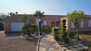 A residential house with a garage, a stone pathway, and various shrubs. - SEPTEMBER SPECIAL: Vacation Rental in St Gilles Croix de Vie (Le Fenouiller)