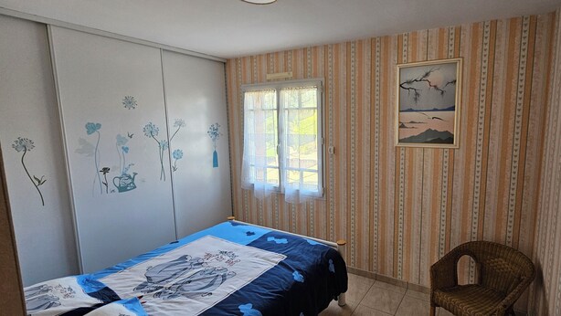 A bedroom with a bed, a chair, a window, and a wall with a painting. - SEPTEMBER SPECIAL: Vacation Rental in St Gilles Croix de Vie (Le Fenouiller)