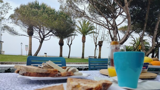 Una mesa con un sándwich, un vaso de jugo y un cuchillo.
