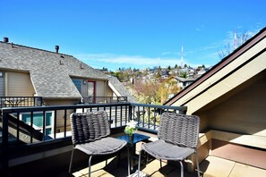Ein Balkon mit zwei Korbstühlen, einem kleinen Tisch und einem Blumentopf.