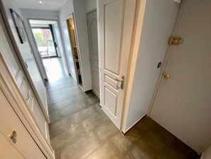 A hallway with a door, a light switch, and a view into another room. - Le Corbier lodge 43 2-bedroom apartment at the foot of the slopes (Villarembert)