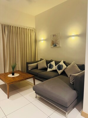 A modern living room with a sofa, a coffee table, and a potted plant. - Latitude Luxury Seafront Apt (Grande Riviere Noire)