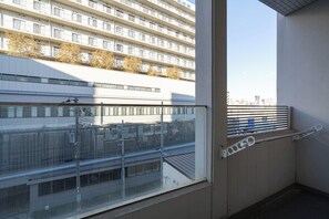 Ein Balkon mit Metallgeländer, Blick auf ein Gebäude mit vielen Fenstern und einem klaren Himmel.