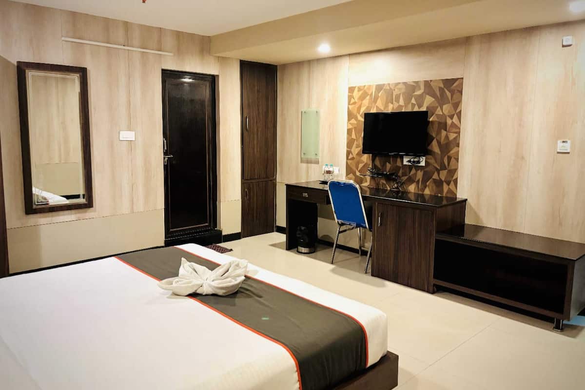 Habitación de hotel con cama, escritorio, silla, televisor y armario.