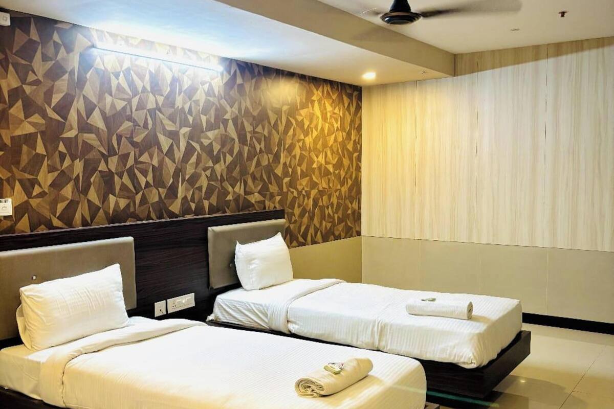 Habitación de hotel con dos camas, un ventilador de techo y una pared con diseño geométrico.