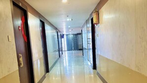 A long, well-lit corridor with doors on both sides, leading to a distant room. - Rosee Wood (Visakhapatnam)