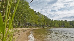 Näkymä järvelle, jota reunustaa hiekkapolku, joka johtaa riviin mökkejä.