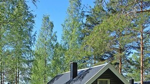 Mökki, jossa on kalteva katto, savupiippu ja pieni kuisti.