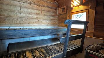 Interior de una cabaña de madera con un banco, una ventana y una estufa.