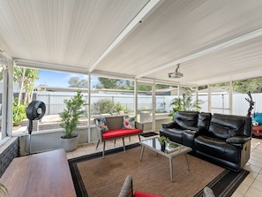 En overdækket terrasse med sofa, sofabord og ventilator.