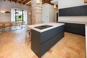 Een moderne keuken met een centraal eiland, barkrukken en uitzicht op het buiten.
