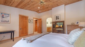 Een slaapkamer met een bed, houten plafond, open haard en een bureau.