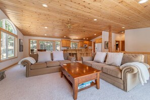 Ein gemütliches Wohnzimmer mit Holzboden, zwei Sofas, einem Couchtisch und einer Küchenzeile mit Holzschränken.