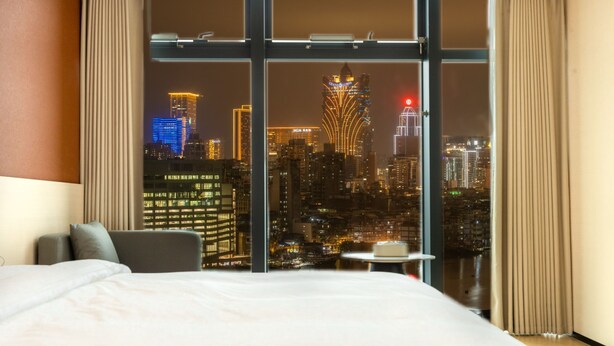 A hotel room with a large window offering a cityscape view at night. - Zhuhai Yueao Cross-Border Hotel - Zhuhai Branch (Zhuhai)