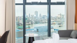 A hotel room with a large window, a bed, a small table, and a chair. - Zhuhai Yueao Cross-Border Hotel - Zhuhai Branch (Zhuhai)