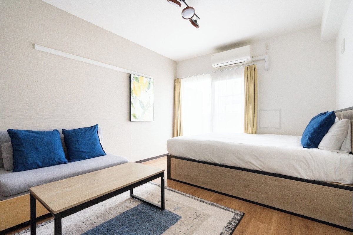 Una habitación de hotel con sofá, cama, una mesita y ventana con cortinas.