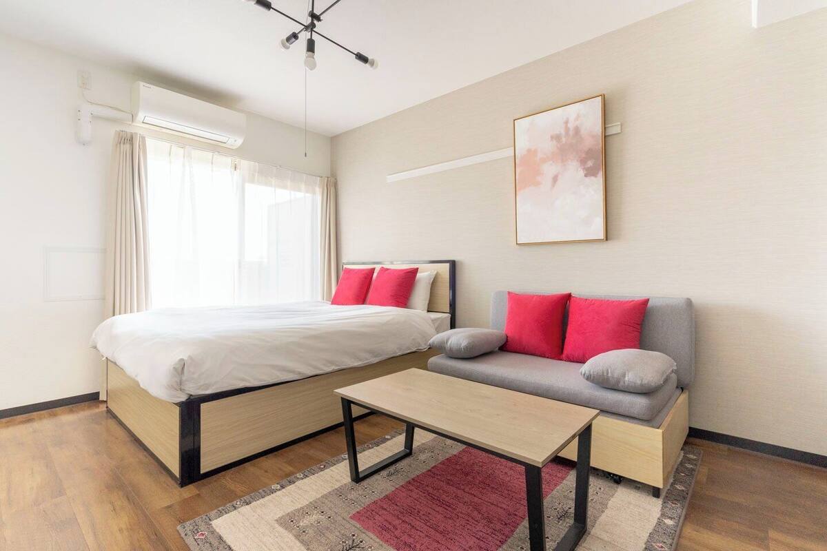 Una habitación de hotel moderna con una cama, un sofá, una mesa de centro y un cuadro en la pared.