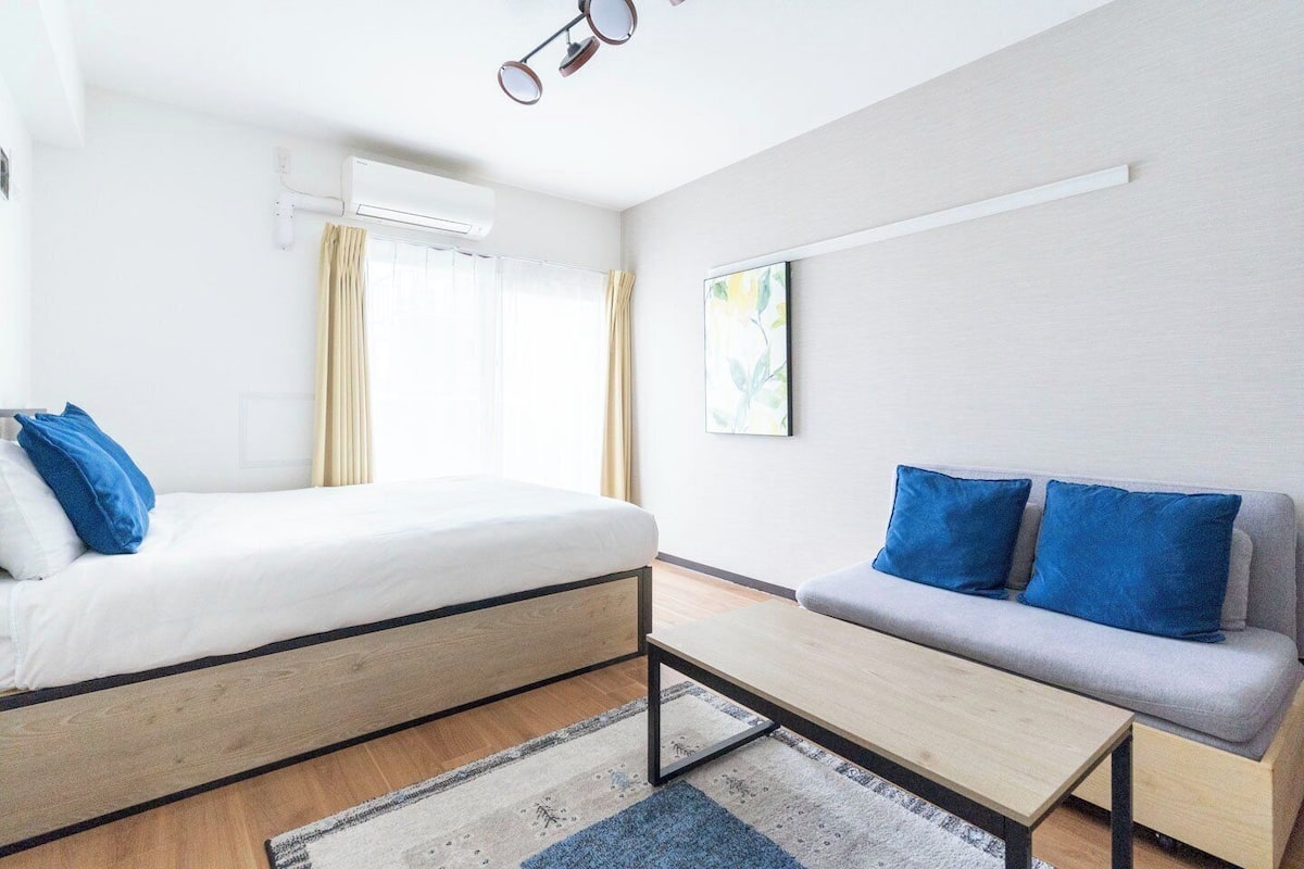 Una habitación de hotel moderna con cama, sofá y una pequeña mesa.