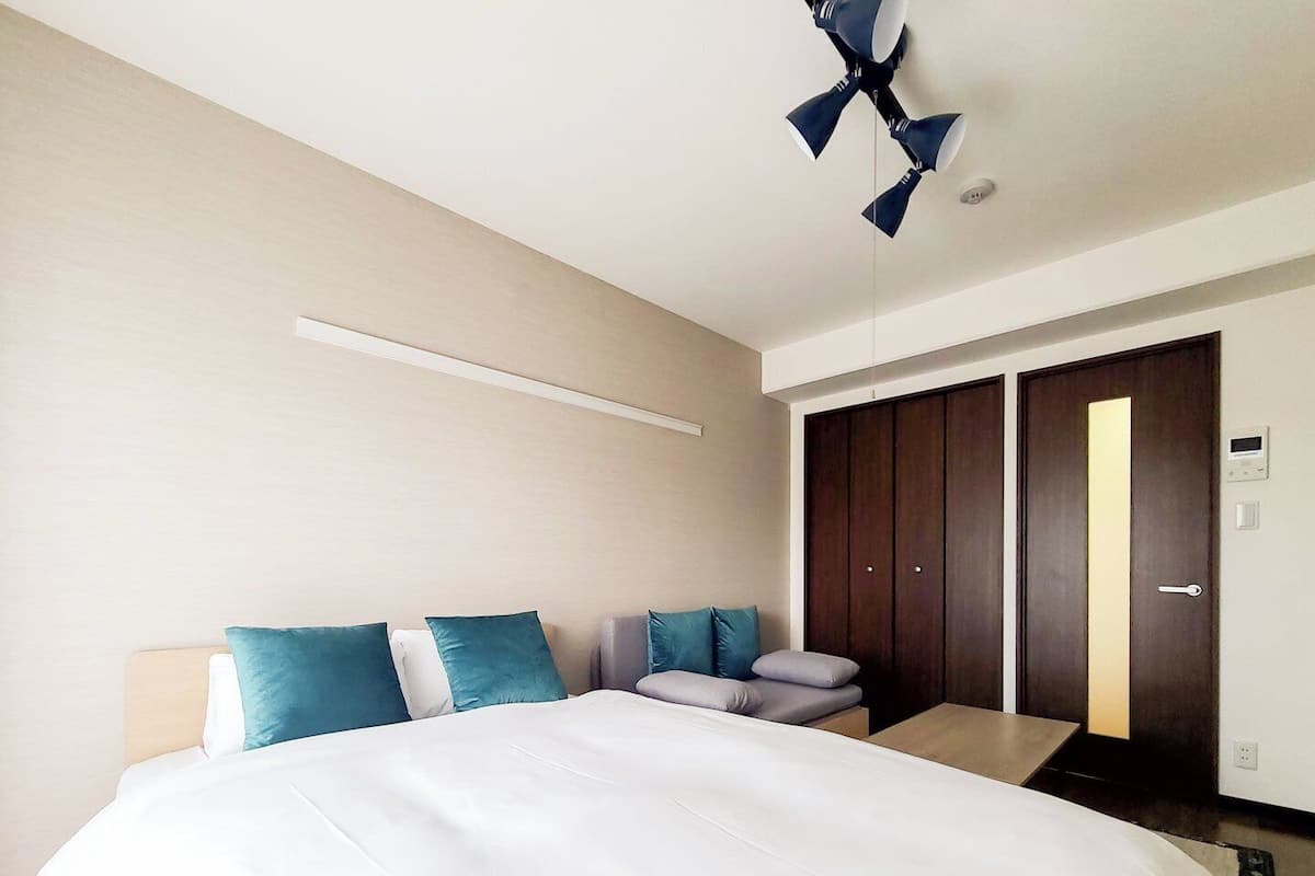Habitación de hotel con cama, mesita de noche, armario y ventilador de techo.